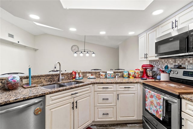 kitchen with sink, light stone counters, hanging light fixtures, stainless steel appliances, and backsplash