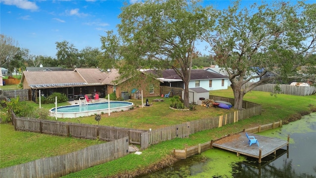 back of property featuring a fenced in pool, a lawn, and a shed