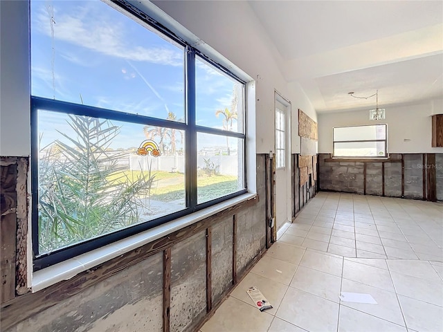 hallway with light tile patterned floors, a chandelier, and vaulted ceiling