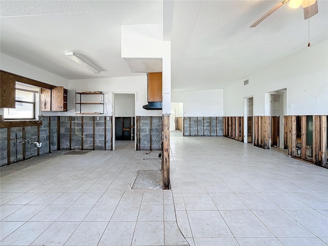 interior space featuring ceiling fan, light tile patterned floors, and a textured ceiling