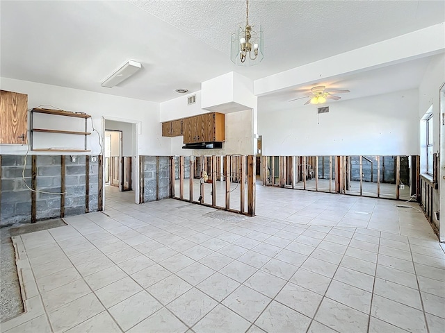 spare room with a textured ceiling and ceiling fan with notable chandelier