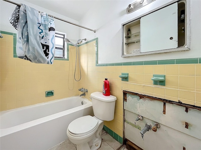 bathroom with tile patterned flooring, tiled shower / bath, toilet, and tile walls