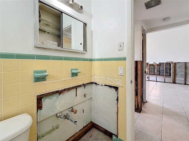 bathroom featuring tile patterned flooring, tile walls, and toilet