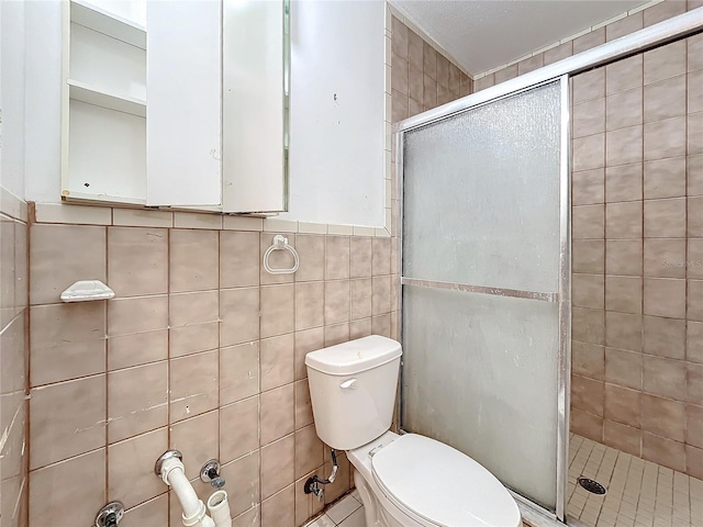 bathroom featuring toilet, tile walls, and a shower with shower door