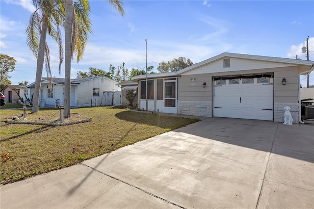 view of front of property featuring a garage, a front lawn, and a sunroom