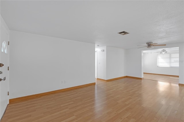 empty room with ceiling fan, light hardwood / wood-style floors, and a textured ceiling