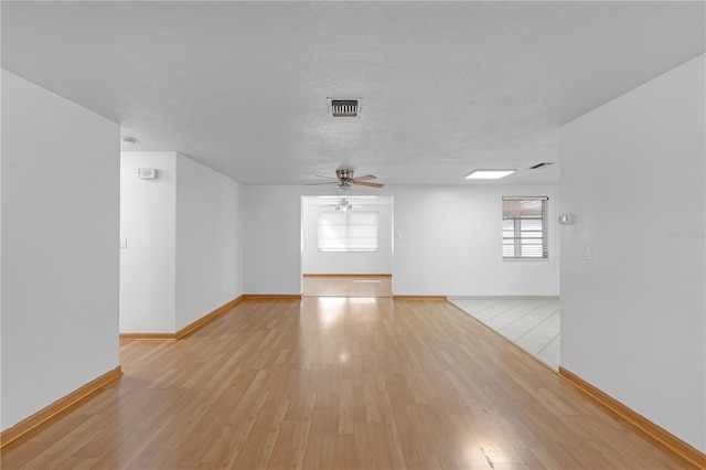 unfurnished room with a textured ceiling, light wood-type flooring, and ceiling fan