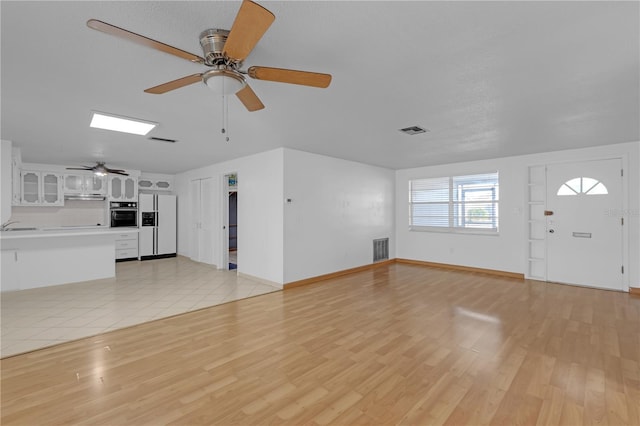 unfurnished living room featuring ceiling fan and light wood-type flooring