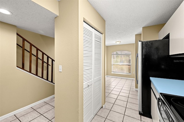 kitchen with stove, light tile patterned floors, and a textured ceiling