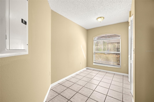 empty room featuring light tile patterned floors, a textured ceiling, and electric panel