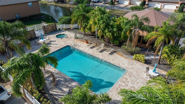 view of swimming pool featuring a water view, a patio, and a hot tub