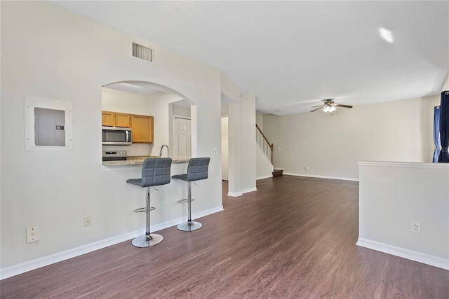 living room with dark wood-type flooring, sink, electric panel, and ceiling fan