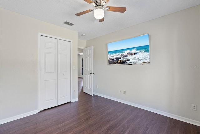 unfurnished bedroom with dark hardwood / wood-style floors, a textured ceiling, ceiling fan, and a closet