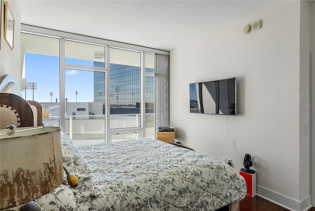 bedroom featuring multiple windows, hardwood / wood-style floors, and floor to ceiling windows