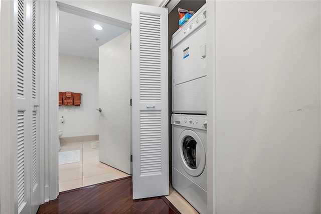 laundry room with tile patterned flooring and stacked washer and dryer