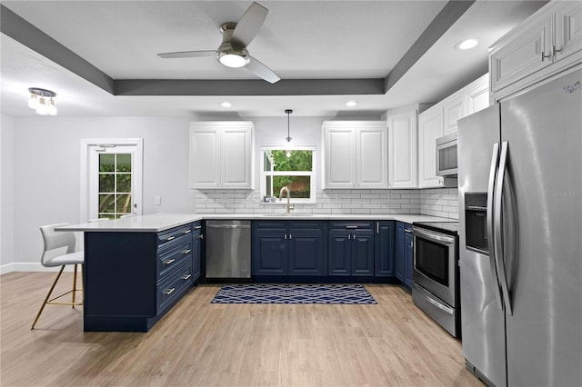 kitchen featuring blue cabinetry, kitchen peninsula, white cabinets, and appliances with stainless steel finishes