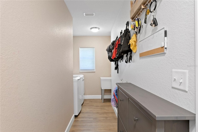 interior space featuring sink, washer and clothes dryer, and light hardwood / wood-style flooring