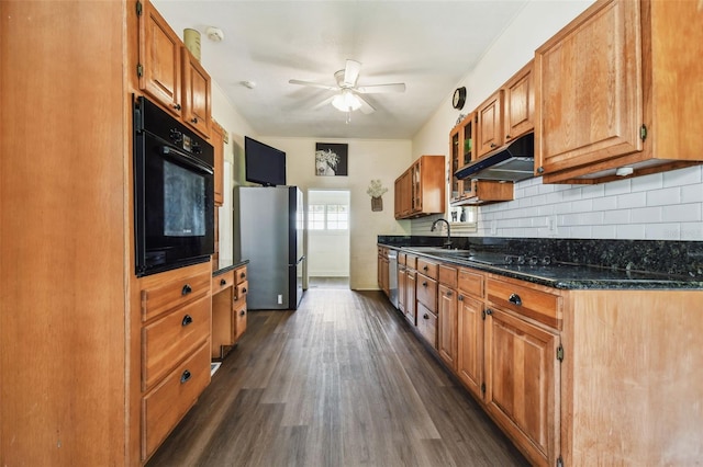 kitchen featuring ceiling fan, dark hardwood / wood-style floors, dark stone counters, decorative backsplash, and appliances with stainless steel finishes