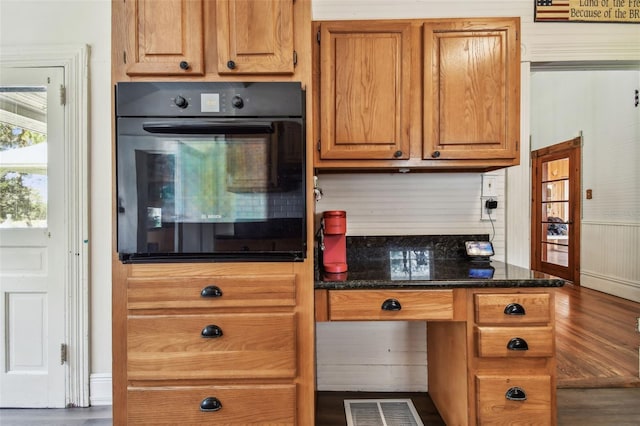 kitchen with oven and dark stone counters