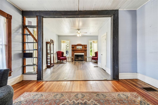 living room featuring ceiling fan, beam ceiling, and wood-type flooring