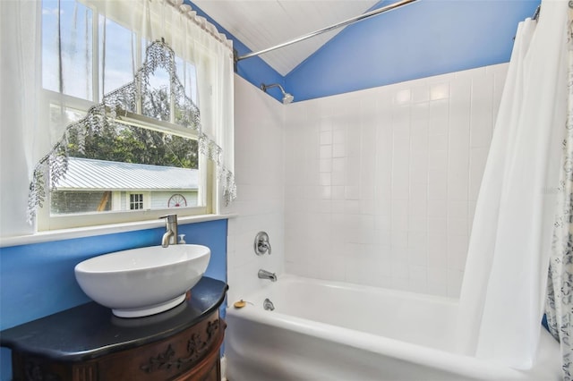 bathroom featuring vanity, vaulted ceiling, and shower / bath combo with shower curtain