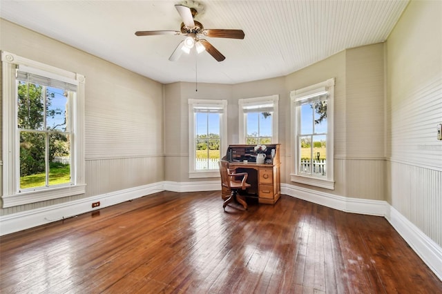 unfurnished office with a wealth of natural light, ceiling fan, and dark wood-type flooring