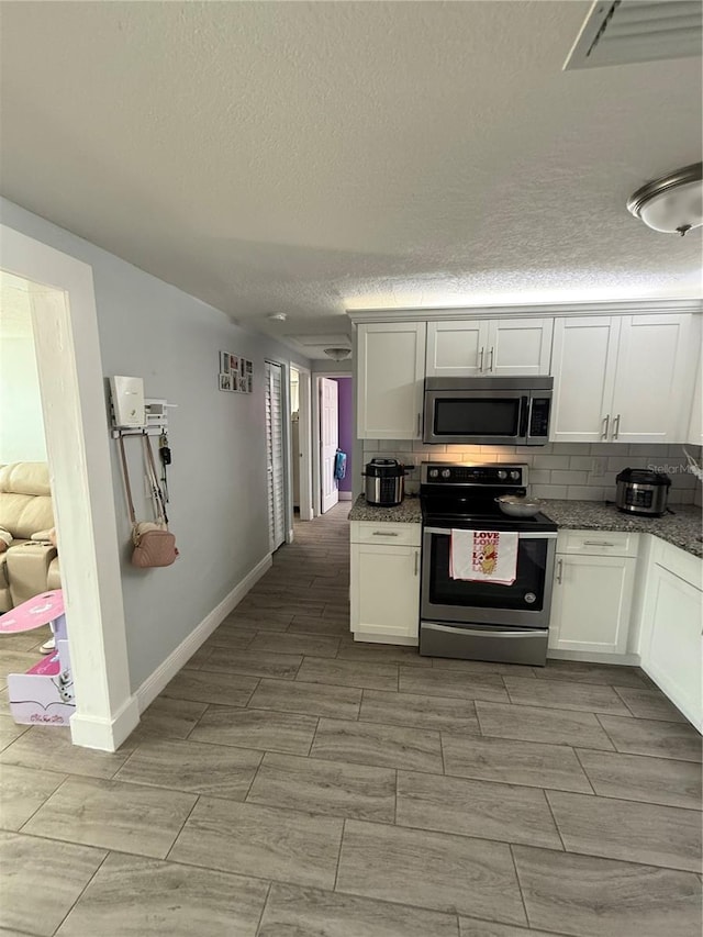 kitchen with white cabinetry, backsplash, and appliances with stainless steel finishes