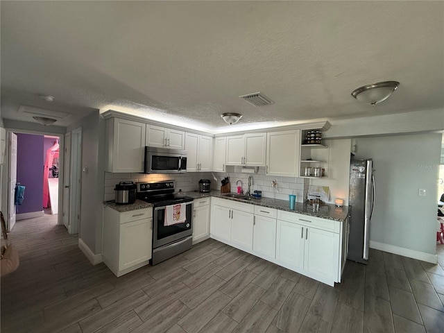 kitchen with white cabinetry, sink, stainless steel appliances, dark stone countertops, and decorative backsplash