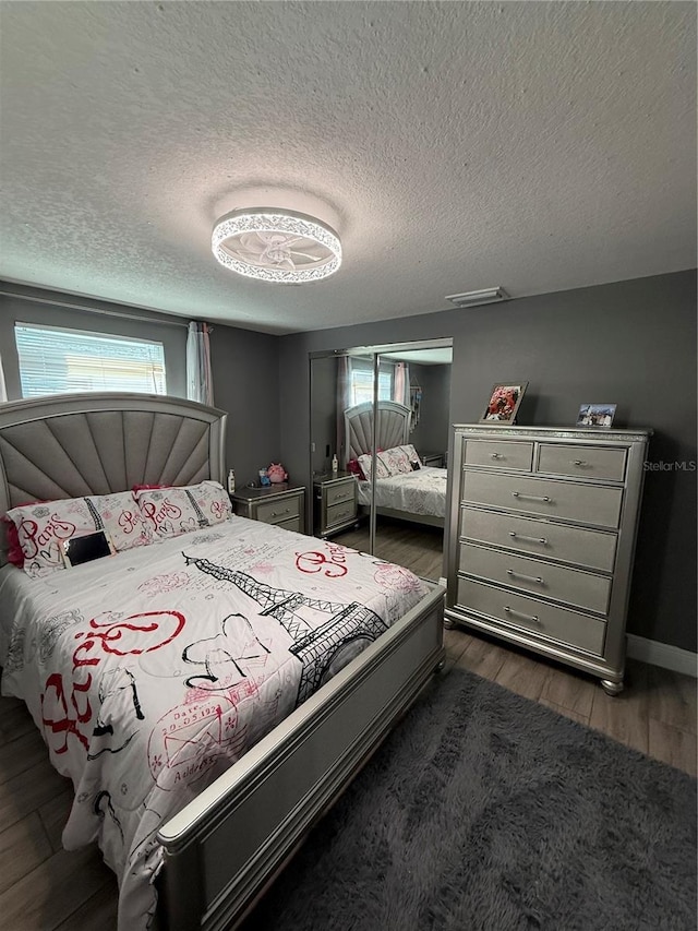 bedroom with a textured ceiling and dark wood-type flooring