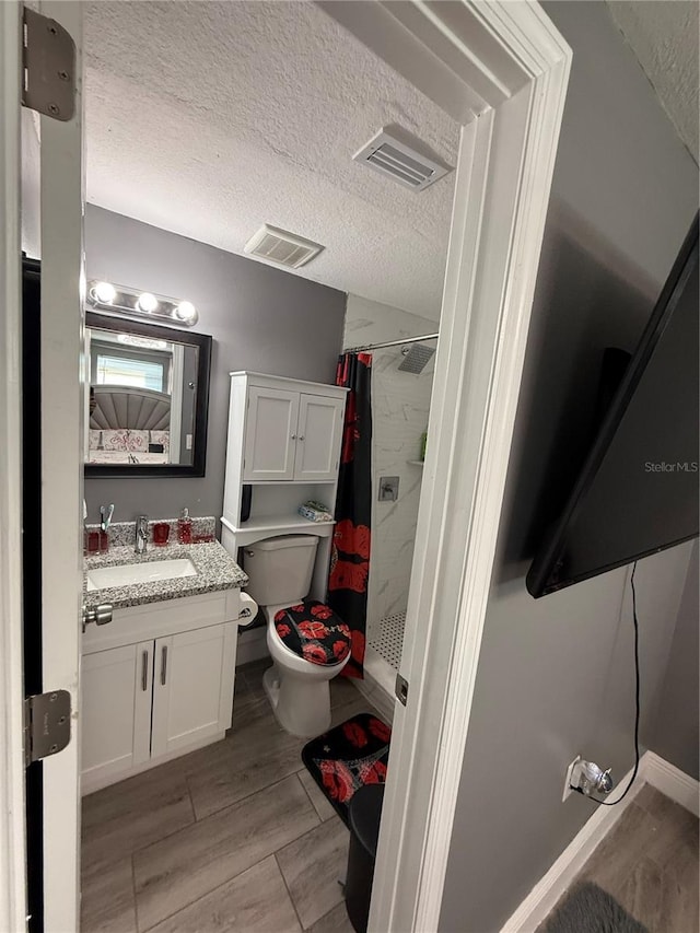 bathroom featuring vanity, curtained shower, toilet, and a textured ceiling