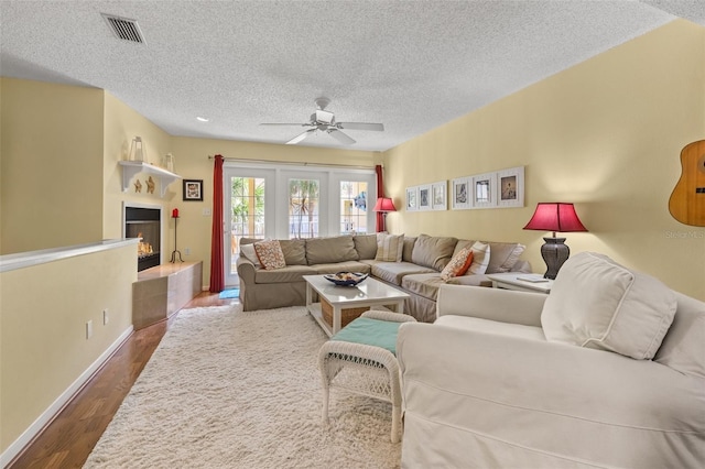 living room with a textured ceiling, hardwood / wood-style flooring, and ceiling fan