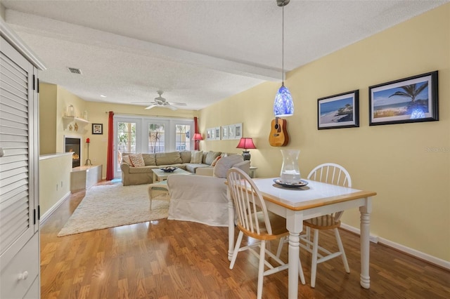 dining space with hardwood / wood-style floors, a textured ceiling, ceiling fan, and beam ceiling