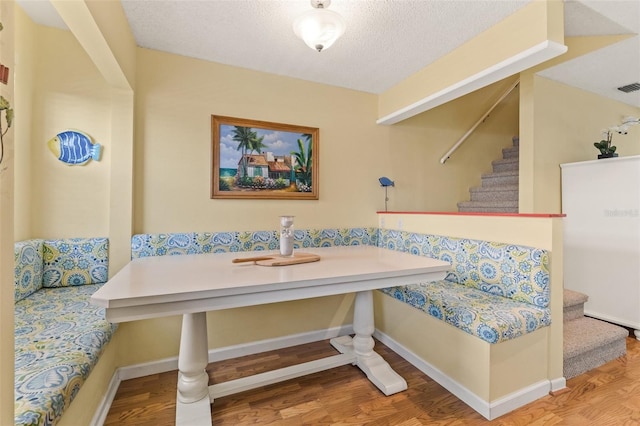 dining room with breakfast area, a textured ceiling, and hardwood / wood-style flooring