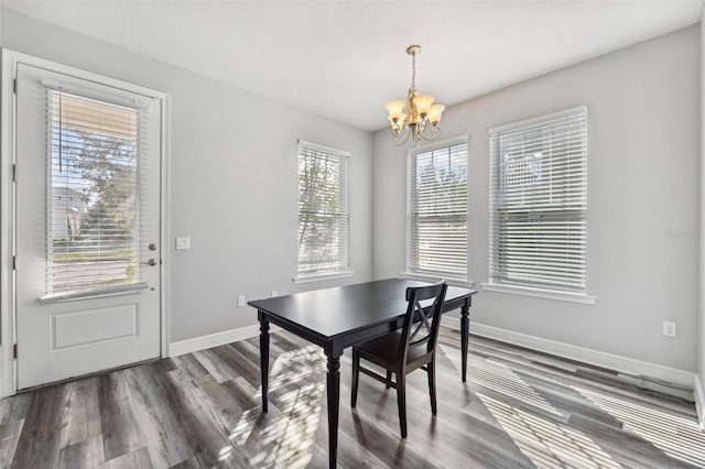 dining space featuring a healthy amount of sunlight, dark wood-type flooring, and a chandelier