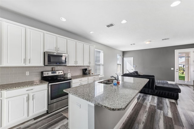 kitchen with white cabinetry, sink, stainless steel appliances, backsplash, and a kitchen island with sink