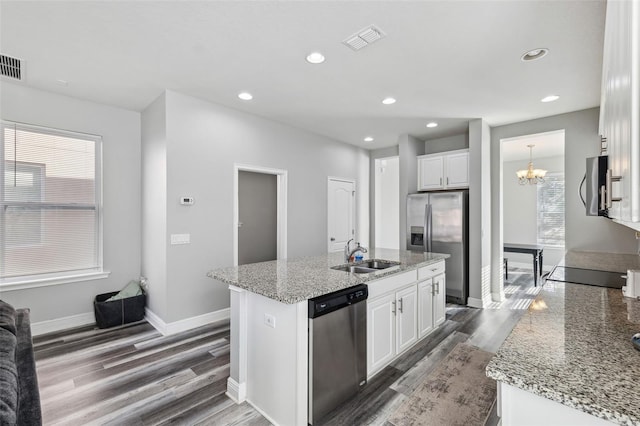 kitchen with a center island with sink, sink, light stone countertops, appliances with stainless steel finishes, and white cabinetry