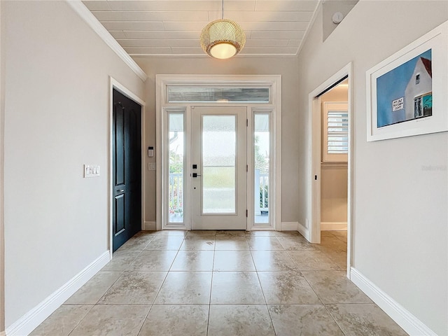 entryway with ornamental molding and light tile patterned floors