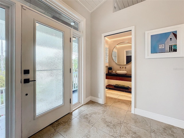 doorway to outside with a healthy amount of sunlight, lofted ceiling, and light tile patterned floors