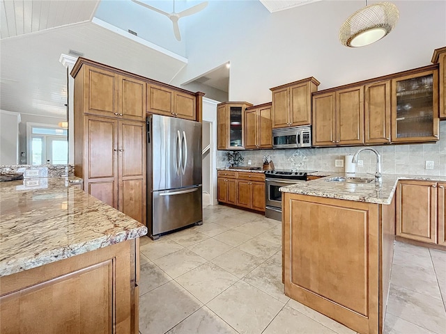 kitchen with sink, light stone counters, lofted ceiling, backsplash, and appliances with stainless steel finishes