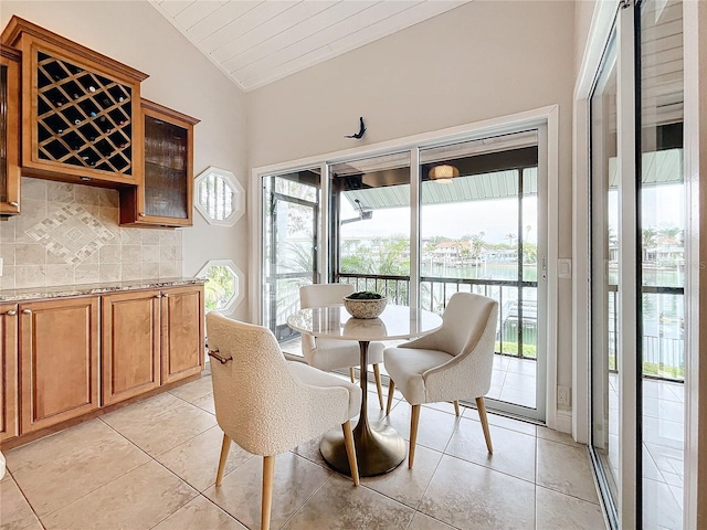 dining room with lofted ceiling, light tile patterned floors, and a water view