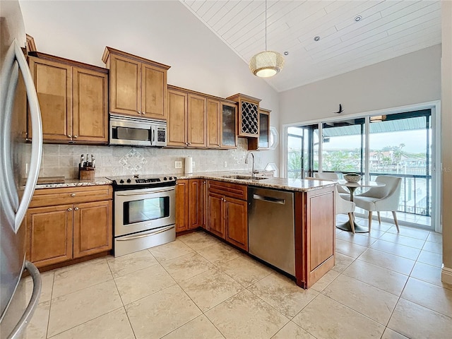 kitchen featuring sink, tasteful backsplash, light stone countertops, pendant lighting, and appliances with stainless steel finishes