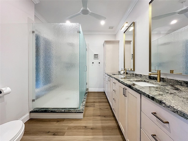 bathroom with wood-type flooring, walk in shower, crown molding, vanity, and ceiling fan