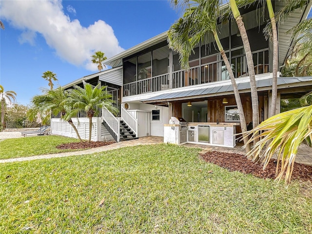 back of property featuring a yard, area for grilling, and a sunroom