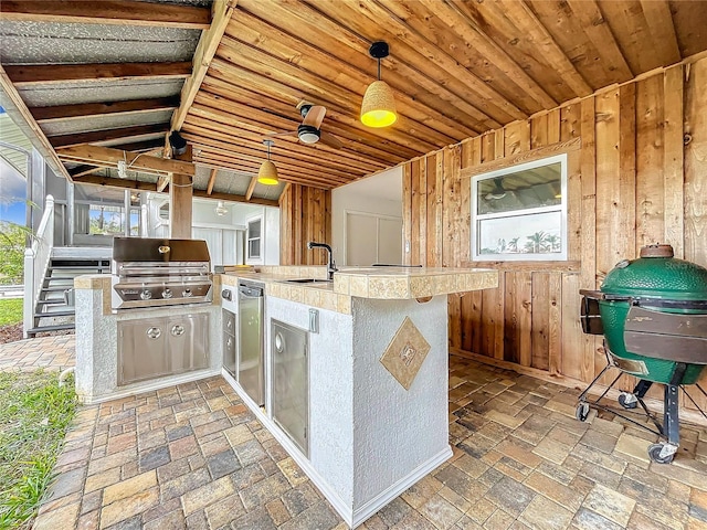 kitchen with wood walls, hanging light fixtures, plenty of natural light, sink, and fridge