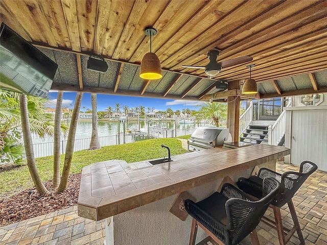 view of patio with sink, area for grilling, and a water view