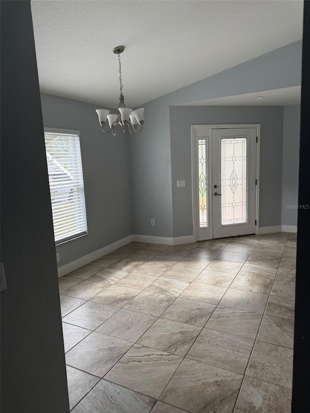 entryway featuring a chandelier, a textured ceiling, and vaulted ceiling