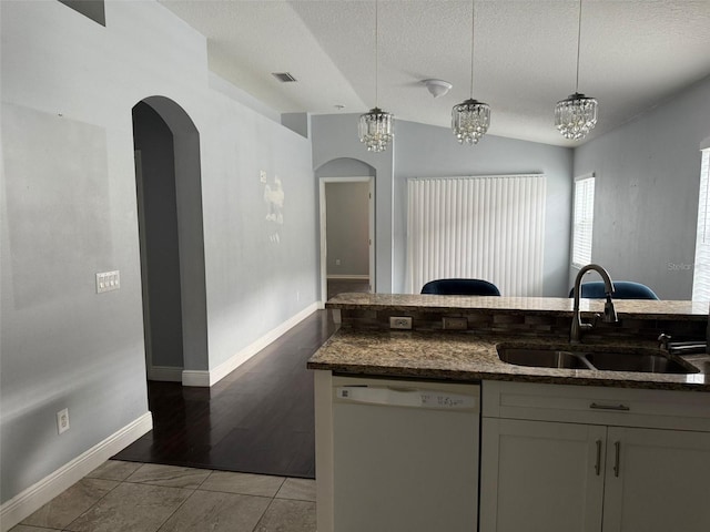 kitchen with decorative light fixtures, white dishwasher, dark stone counters, and sink