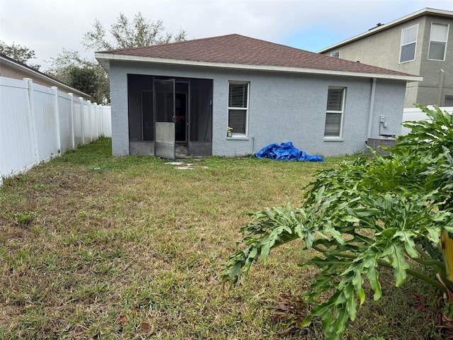 rear view of property featuring a lawn and a sunroom