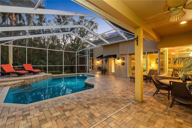 pool at dusk featuring ceiling fan, a lanai, and a patio area