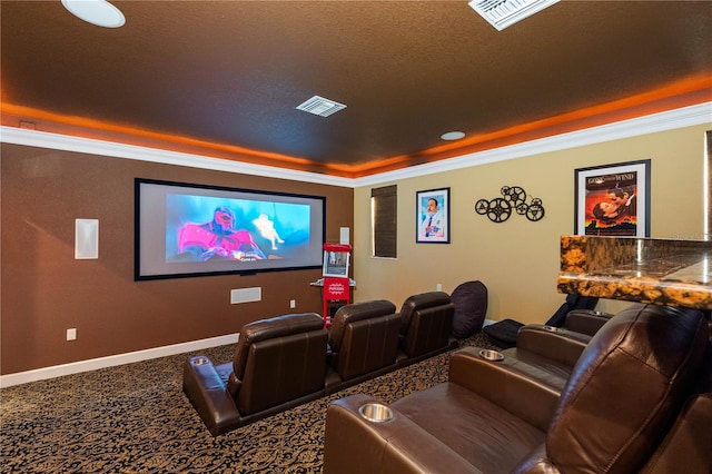 carpeted cinema room with ornamental molding, a raised ceiling, and a textured ceiling